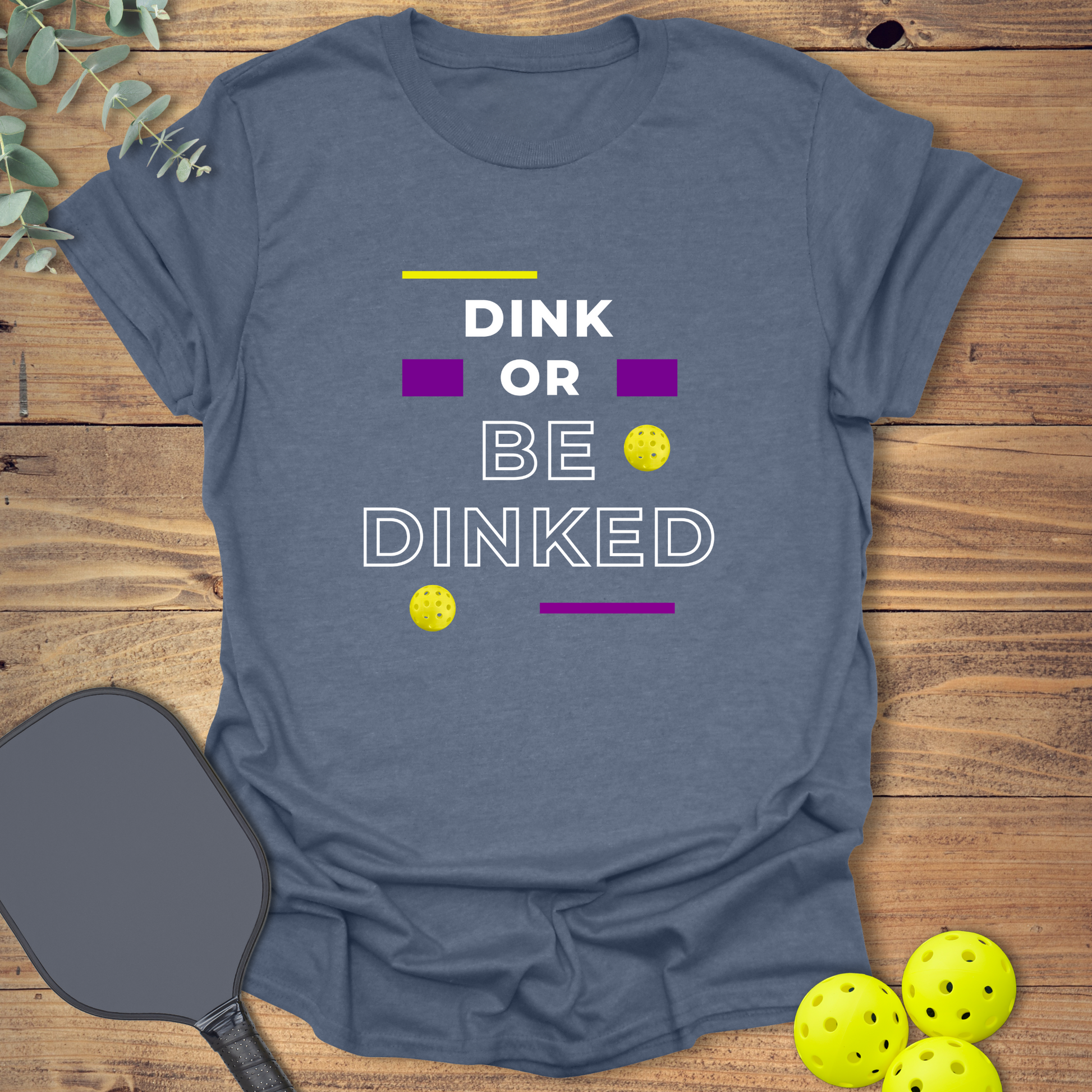 Heather indigo pickleball t-shirt with the phrase “Dink or Be Dinked” in bold white, purple, and yellow text, accented with small yellow pickleballs.