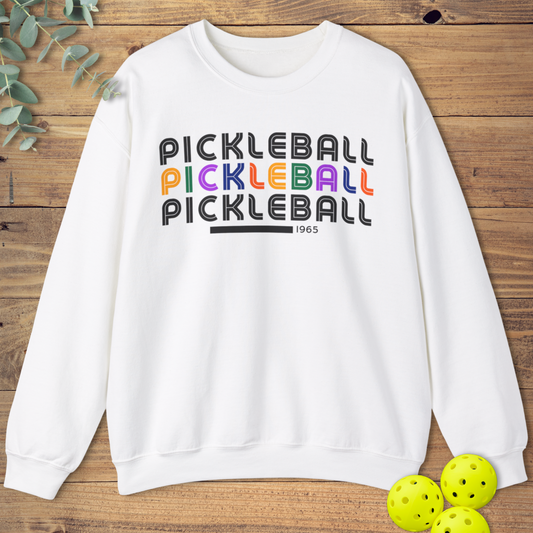 Unisex sweatshirt with the word “Pickleball” repeated three times in stacked retro-style text in orange, pink, and yellow. Cozy and colorful design for pickleball fans.