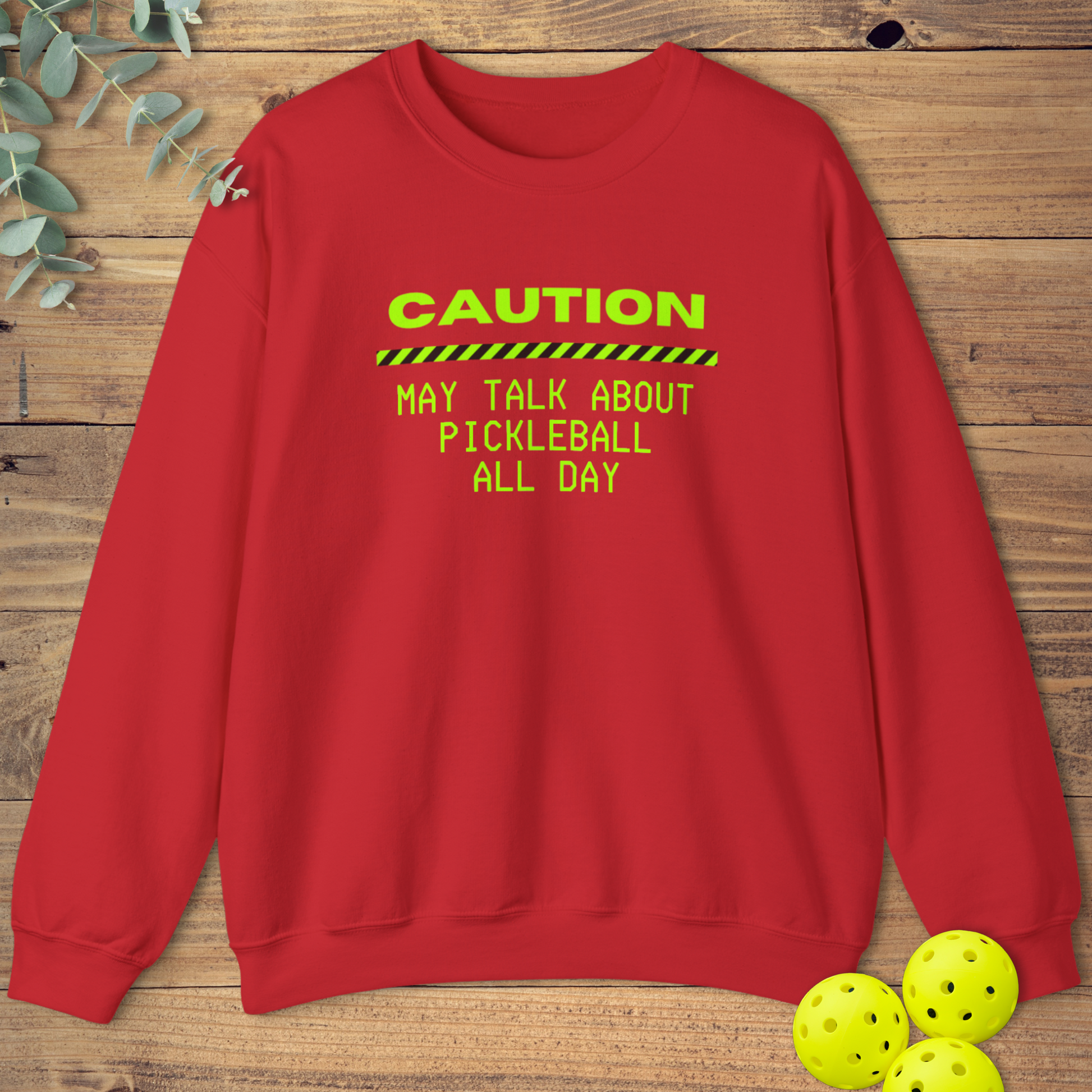 Red pickleball sweatshirt with neon green text that reads “Caution: May Talk About Pickleball All Day” and a caution stripe graphic.