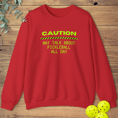Red pickleball sweatshirt with neon green text that reads “Caution: May Talk About Pickleball All Day” and a caution stripe graphic.