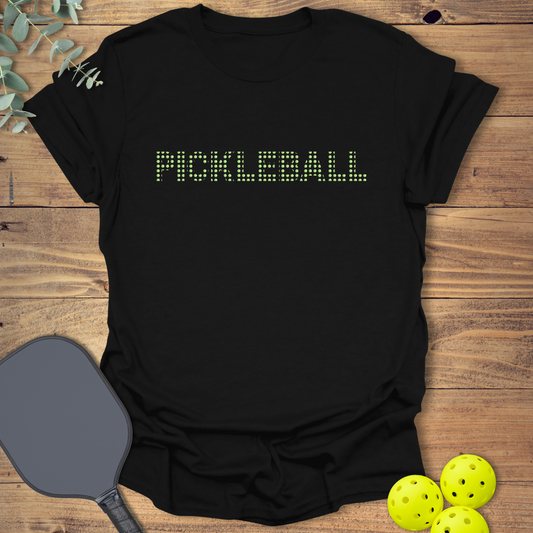 Black unisex t-shirt with the word “Pickleball” in a pixel-style font made from mini pickleballs. Fun graphic shirt for pickleball lovers.